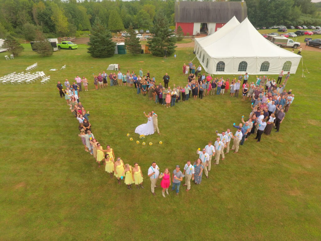 Aerial photo of wedding attendees standing in a heart